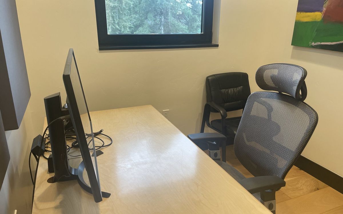 Private Office 9 upstairs — sit-stand desk with a monitor, task chair and a guest chair by the window