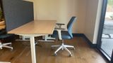 The same dedicated desk from the side, showing the sit-stand frame and the felt divider to its neighbour