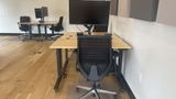 The same dedicated desk from the side, showing the sit-stand frame and floor mat