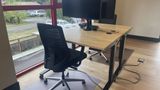 The same dedicated desk from the side, showing the sit-stand frame and floor mat