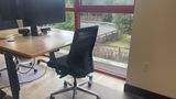 The same dedicated desk from the side, showing the sit-stand frame and floor mat