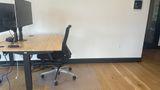 The same dedicated desk from the side, showing the sit-stand frame and floor mat