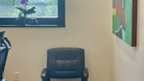 Leather guest chair beneath the window, next to an abstract canvas