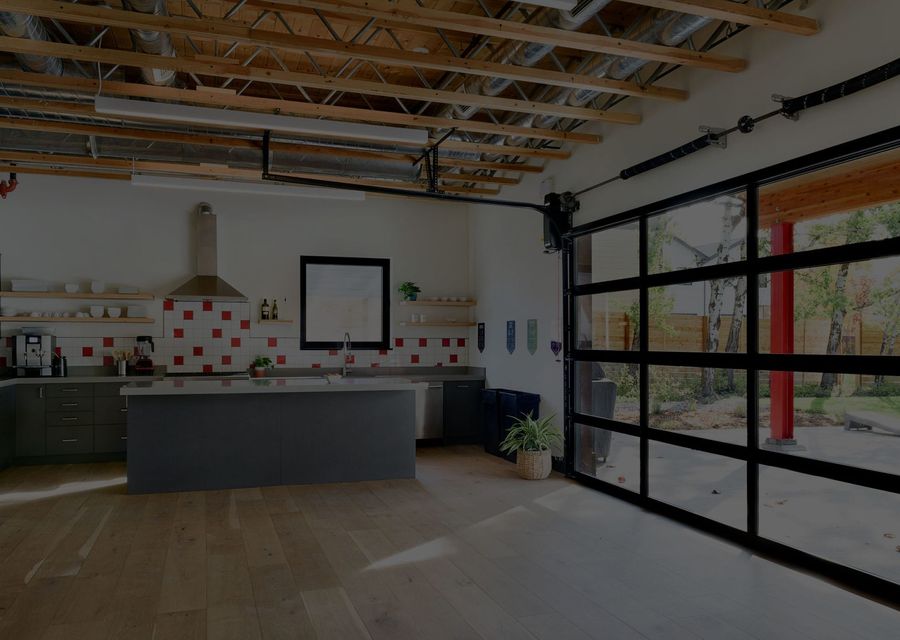 Kitchen island with range hood and glass garage doors opening to the outdoors
