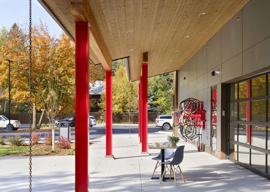 Covered outdoor patio with red steel columns, seating, and bike racks