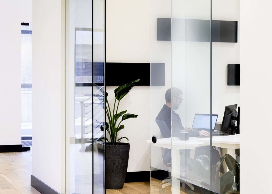 Glass-walled private office with a desk and chair