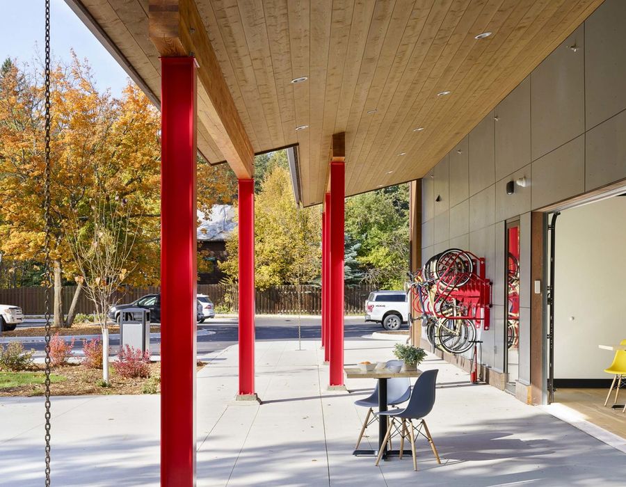 Covered patio seating under red steel columns in autumn